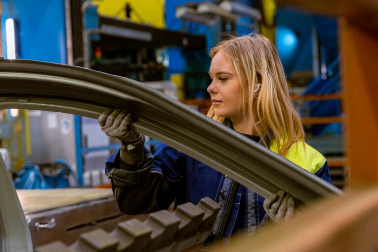 EBP reservdelar för fordonsindustrin: medarbetare kontrollerar en böjd, pressad karossplåt vid verktygslinan.
